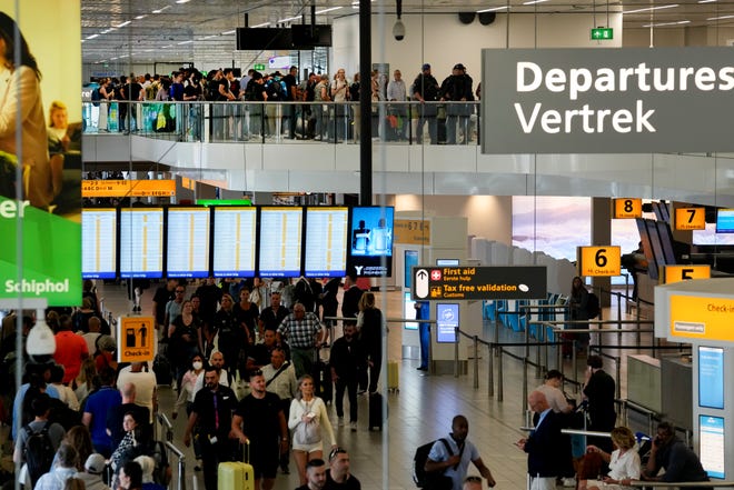 Travelers wait in long lines to check in and board flights at Amsterdam's Schiphol Airport, Netherlands, on June 21, 2022.