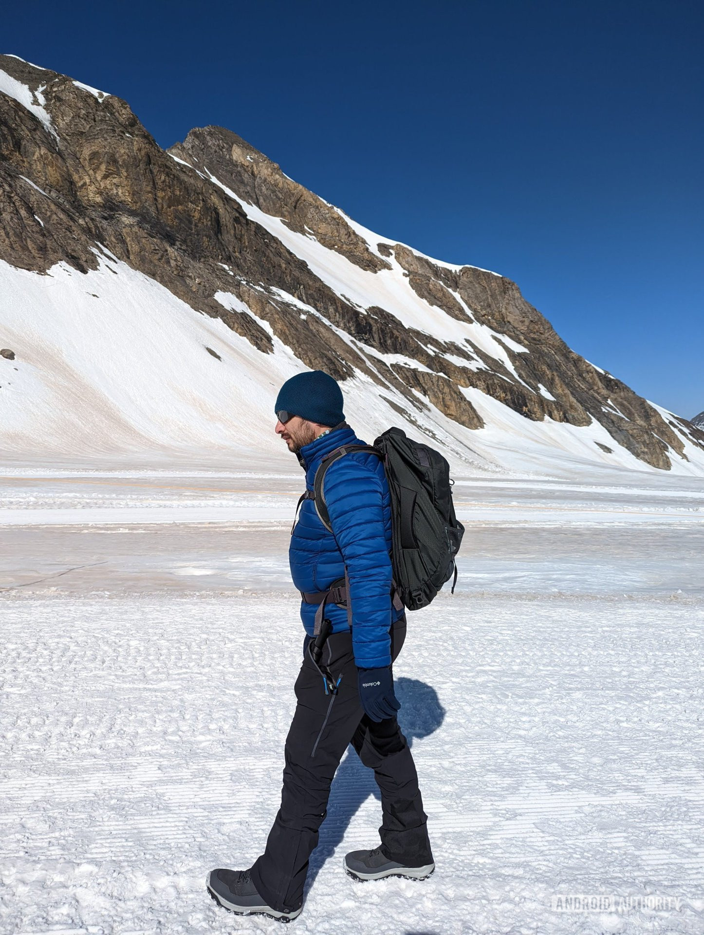 Man walking in the snow with the Osprey Farpoint backpack on his back